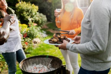 People standing round a barbecue in a sunny garden
